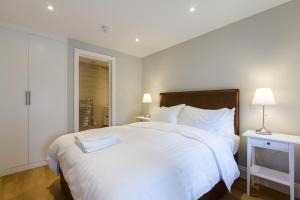 泰晤士河畔金斯顿狮子门马厩酒店的卧室配有一张白色大床和两盏灯。