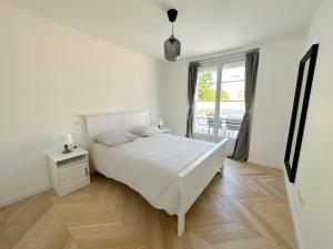 拉罗谢尔Les appartements du Carnot - Terrasses et Jardins的白色的卧室设有床和窗户