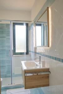 卡普多兰多Magico Apartments - 450m dalla spiaggia的一间带水槽、淋浴和镜子的浴室