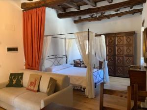 塞尼奥河畔帕拉佐洛La Torre del Vicario的一间卧室配有天蓬床和沙发