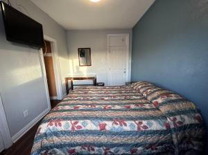 长滩Unity Hotel - No Parking & Rooms Are Upstairs的卧室配有一张床,墙上配有电视。