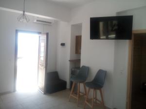 巴特斯欧AMPELOS ANDROS的一间房间,墙上有3把椅子和一台电视