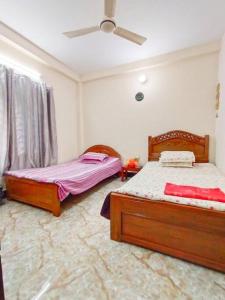 巴纳内拉斯Modern 3 Bedroom Flat in Sylhet的一间卧室配有两张床和吊扇