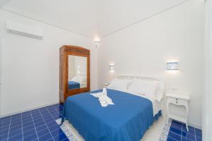 马奥莱Relais Capitolo的一间卧室配有一张带蓝色毯子和镜子的床