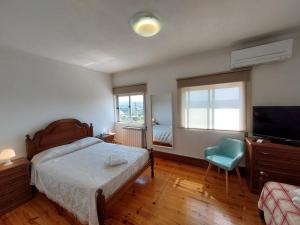 维拉·雷阿尔Casa Machado的一间卧室配有一张床、一台电视和一把椅子