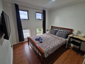 黄金海岸Shared house with other guests near shopping center and theme parks的一间卧室配有一张床、一张书桌和两个窗户。