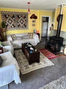 图克劳海滩Karikari Lodge的客厅配有白色沙发和燃木炉。