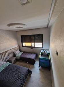 伊穆泽尔杜坎达Chalet villa QUE POUR LES FAMILLES的一间卧室设有两张床、一个窗口和一个行李箱
