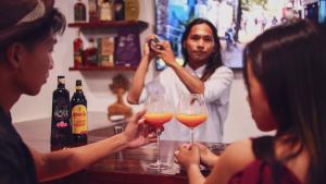 爱妮岛Bebeladan Beach Resort, In The Last Indigenous Corner的一群人坐在酒吧里,戴着酒杯