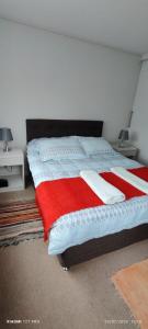 奥索尔诺RUCAMAR的一间卧室配有一张带红白毯子的床