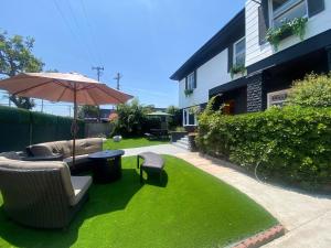 洛杉矶Burlington Hostel的一个带遮阳伞和椅子的庭院和一个草坪