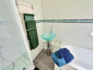 沃勒西New Brighton Beach的浴室设有水槽、浴缸和蓝色毛巾