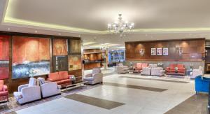 安曼日内瓦酒店的大堂配有沙发、椅子和吊灯