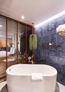 清迈The Moment Chiangmai的浴室配有白色浴缸和蓝色的墙壁
