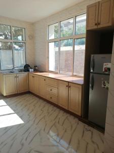 布琼布拉Kajaga Tanganyika的厨房配有木制橱柜、冰箱和窗户。