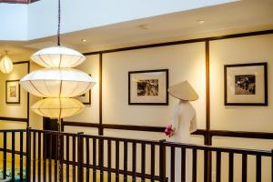 会安Lantana Riverside Hoi An Boutique Hotel & Spa的一只白衣的 ⁇ ,站在一个有两盏灯的房间
