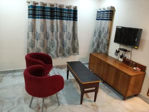 BrahmapurHotel HCB (Hemo Chandra Bhawan)的客厅配有电视、椅子和桌子