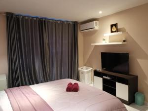 拉威海滩Rawai beachfront - The Title Condominium的一间卧室配有一张床和一台平面电视