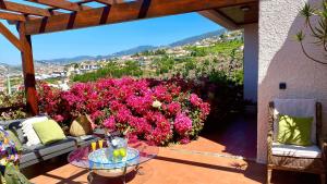 丰沙尔Casa ideal para famílias com vista mar desafogada的一个带粉红色花卉和玻璃桌的庭院
