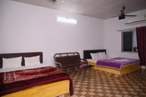 卡齐兰加Chang Ghar Resort的一间设有两张床和椅子的房间