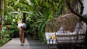 暹粒林纳雅都市河滨度假酒店的走在花园走道上的女人