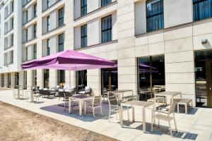 达姆施塔特Premier Inn Darmstadt City Centre的一座配有桌椅和紫色雨伞的建筑