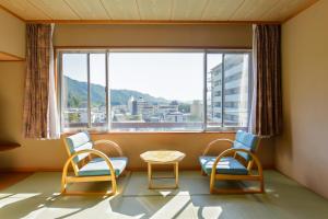 日光Ooedo Onsen Monogatari Hotel Kinugawa Gyoen的客房设有两把椅子、一张桌子和大窗户