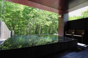 JozankeiSuigan的客房内的热水浴池,享有树林美景