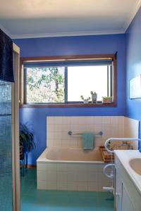 SilvanTreetops - Yarra Valley Country Apartment的蓝色的浴室设有浴缸和窗户。