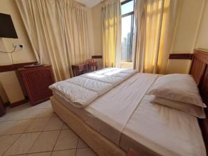 莫希Moshi Leopard Hotel的卧室配有一张大白色床和窗户