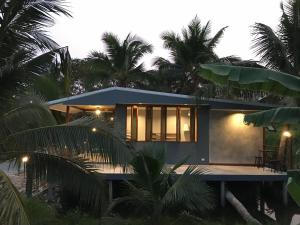 Ban Mo Kaeng TaekCOCO HOME Homestay(โคโค่โฮม)的棕榈树海滩上的房子