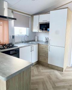 ChwilogHafan Y Môr Caravan - Pwllheli的厨房配有白色橱柜和白色冰箱。