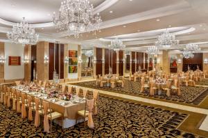 新德里Shangri-La Eros New Delhi的一个带桌子和吊灯的大型宴会厅