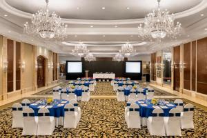 新德里Shangri-La Eros New Delhi的宴会厅配有蓝白桌子和吊灯