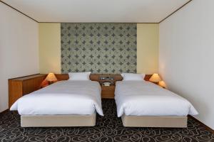 久留米市Suikouen Hotel的配有白色床单的酒店客房内的两张床