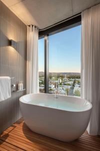 阿德莱德Vibe Hotel Adelaide的带浴缸的浴室和大窗户
