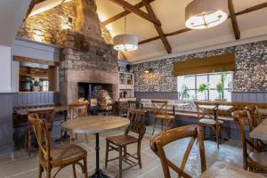 比德内尔The Craster Arms Hotel in Beadnell的餐厅设有木桌和椅子,拥有砖墙