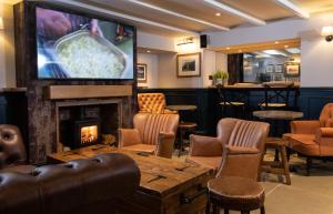 比德内尔The Craster Arms Hotel in Beadnell的一间带壁炉的酒吧以及客房内的电视
