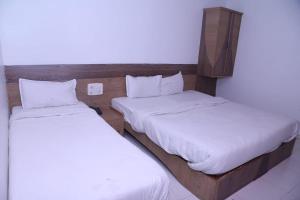 JālgaonHotel Kewal INN的小客房内的两张床,配有白色床单