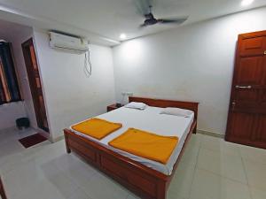 胡布利STAYMAKER Shri Shakti Residency的一间卧室配有一张带橙色床单的床和风扇