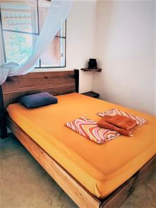 蓬塔乌巴Terra NaturaMa - off grid living in the jungle的一张带橙色床单的大床和窗户