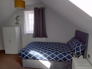 Cosy & Spacious 4 Bedroom House with Free Parking in Birmingham的一间卧室配有一张带蓝色棉被的床和窗户。