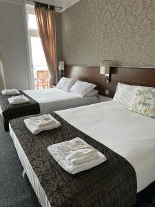 伊斯特布恩格拉斯顿伯里酒店的两张位于酒店客房的床,配有毛巾