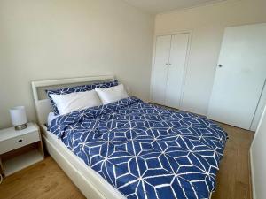 丹德农Central Apartment near Dandenong Hospital & Market的一间卧室配有一张带蓝色和白色棉被的床