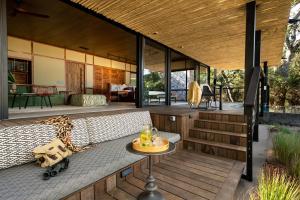 提姆巴瓦提禁猎区Tanda Tula Safari Camp的甲板上的房子,配有沙发和桌子