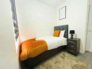 莱斯特Opal Apartment的一间卧室配有一张带橙色毯子和床头柜的床。