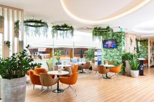 卡托维兹波赞托沃运动酒店的一间设有桌椅的餐厅,种植了植物