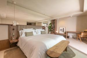 马贝拉Anfitrión Villas & Suites的卧室配有白色大床和木凳