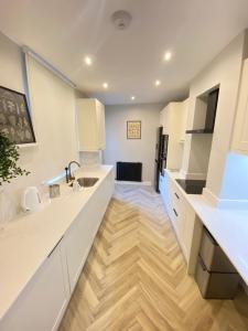 伦敦Luxury 2 bed 1 bath in Central London by Graceful Apartments的厨房铺有木地板,配有白色橱柜。