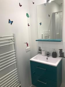 罗什福尔LA MAISON DU BONHEUR的浴室设有水槽、镜子和蝴蝶,墙上挂着蝴蝶